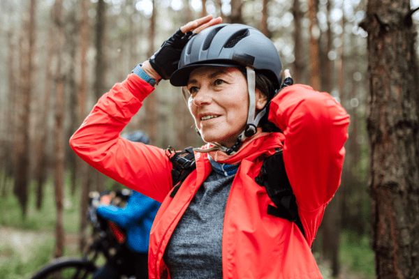 Woman in the forest adjusting her helmet. protect against concussion